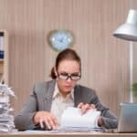 woman searching through papers on her desk