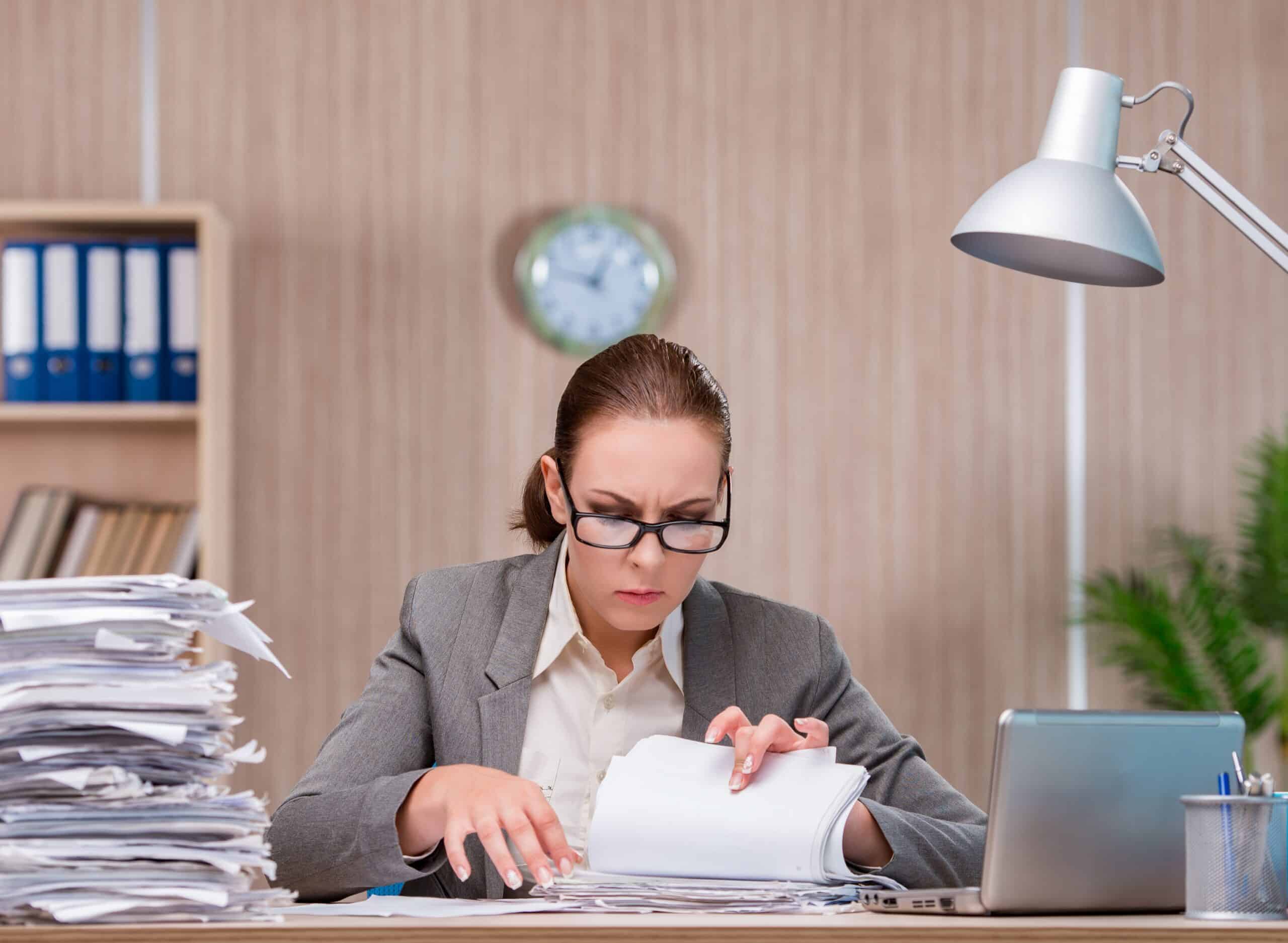 woman searching through papers on her desk